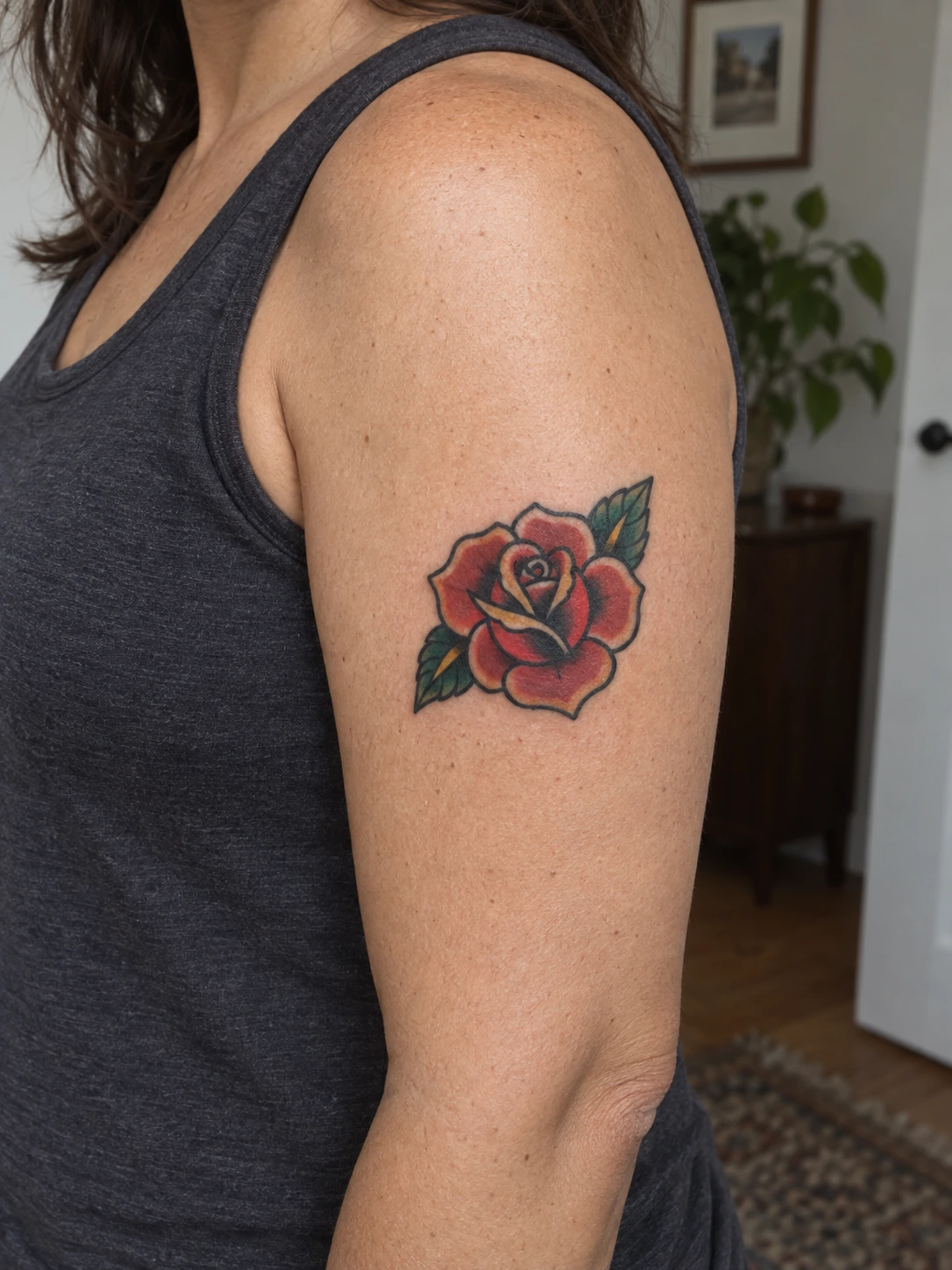 A compact rose leaves open skin around the upper-arm design.
